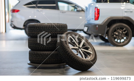 New wheels with studded tires against the background of new cars.  119699873