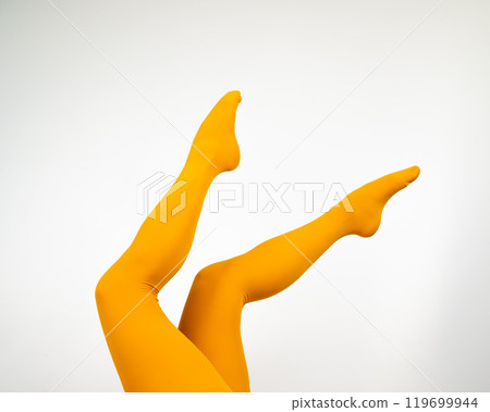 Female legs in ocher tights on a white background.  119699944
