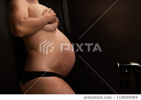 Close-up of the belly of a pregnant woman undergoing an instant tanning procedure. The master applies bronzer with a spray. Close-up of the belly of a pregnant woman undergoing an instant tanning procedure. The master applies bronzer with a spray. 119699969