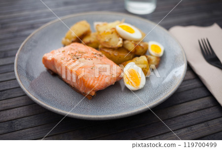 Steamed salmon fillet with potato wedges and quail egg 119700499