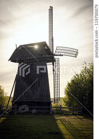 Silhouette of an old wooden windmill on a sunset. Vertical photo 119700879