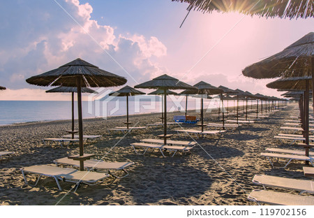 Empty beach with sun loungers and umbrellas in the early morning on a sunny day on the Crete island Greece. Empty beach with sun loungers and umbrellas in the early morning on a sunny day on the Crete island Greece. 119702156