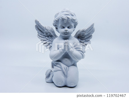 A white angel statue kneels and prays with eyes closed A white angel statue kneels and prays with eyes closed 119702467