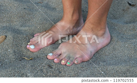 tanned bare female feet with light stripes from sandals on gray fine textured sand, close-up, harmony and relaxation of girl on beach barefoot tanned bare female feet with light stripes from sandals on gray fine textured sand, close-up, harmony and relaxation of girl on beach barefoot 119702555
