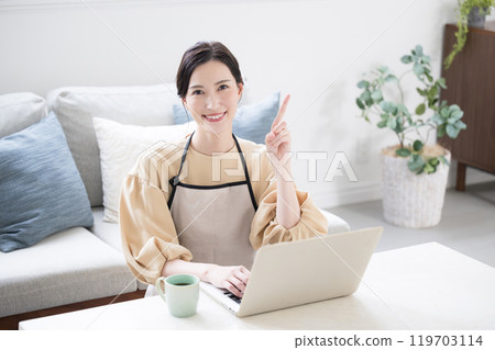 一位家庭主婦在電腦上做家庭會計和工作的圖像 看著相機時的要點和建議的指向姿勢。 一位家庭主婦在電腦上做家庭會計和工作的圖像 看著相機時的要點和建議的指向姿勢。 119703114