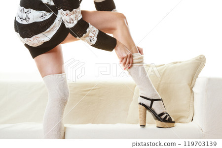 Fashionable girl puts on woolen stockings Fashionable girl puts on woolen stockings 119703139