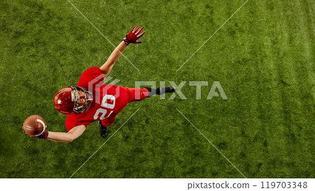 Top view image of concentrated man, American football player in red uniform in motion on stadium, throwing ball with precision 119703348