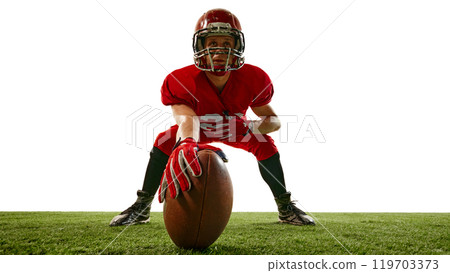Focused man, American football player in helmet and re uniform standing on field with ball, showing determination to win Focused man, American football player in helmet and re uniform standing on field with ball, showing determination to win 119703373