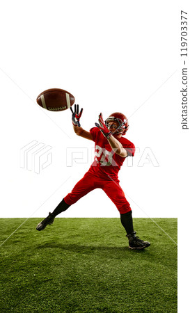 Full-length vertical image of man, American football player in red uniform in motion on field, running and catching ball, training Full-length vertical image of man, American football player in red uniform in motion on field, running and catching ball, training 119703377