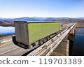 Green truck moving by a bridge over the river 119703389