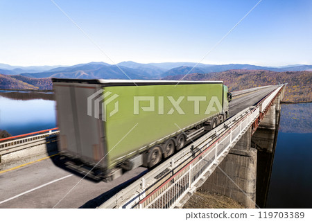 Green truck moving by a bridge over the river 119703389