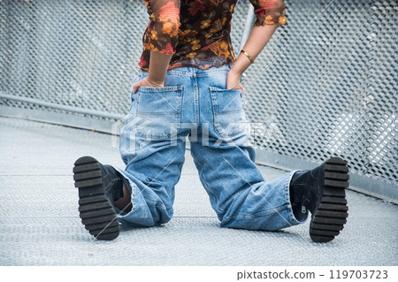 closeup of young woman wearing a large blue jeans  trousers in the street 119703723