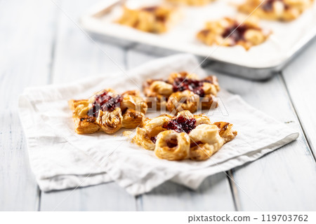 Sweet dessert pastries made of puff pastry with strawberry jam filled with caramelized apple Sweet dessert pastries made of puff pastry with strawberry jam filled with caramelized apple 119703762