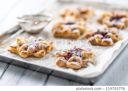 Sweet dessert pastries made of puff pastry with strawberry jam filled with caramelized apple sprinkled with powdered sugar 119703776