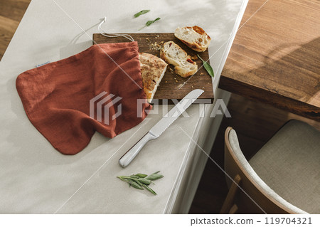Sliced bread on wooden board, linen bag and stainless still kitchen knife. Kitchen aesthetic concept Sliced bread on wooden board, linen bag and stainless still kitchen knife. Kitchen aesthetic concept 119704321
