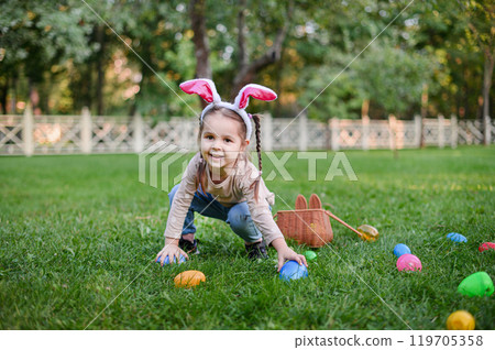 Smiling Little Girl with Bunny Ears and Easter Basket Outdoors Smiling Little Girl with Bunny Ears and Easter Basket Outdoors 119705358