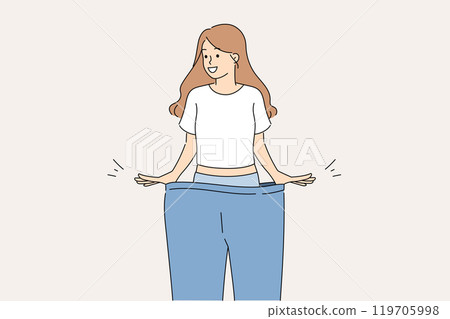 Happy woman lost weight smiles while trying on large size pants and rejoices at progress 119705998