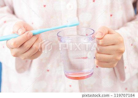 Woman holding a cup and a toothbrush 01 119707184