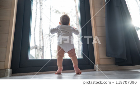 Baby boy standing by the patio window. Baby boy standing by the patio window. 119707390