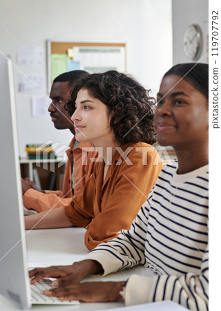 Portrait of diverse group of young professionals collaborating and using computer in modern office environment with books and clock visible in background Portrait of diverse group of young professionals collaborating and using computer in modern office environment with books and clock visible in background 119707792