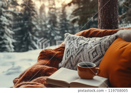 Cozy winter retreat warm blankets, coffee, and a book in a snowy forest 119708005