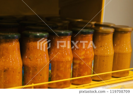 Jars of tomato sauce are organized on a refrigerator shelf 119708709