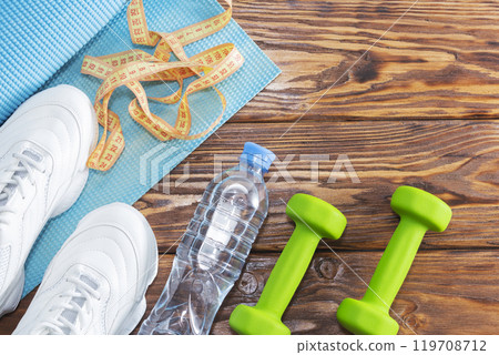 Shoes, water bottle, measuring tape, and dumbbells on a table 119708712