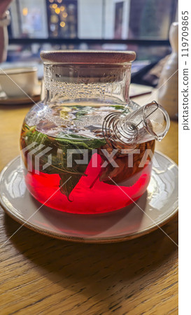 A teapot with hibiscus tea, mint leaves and walnuts. On a table in a cafe. 119709865