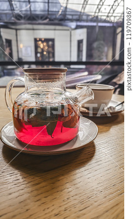 A teapot with hibiscus tea, mint leaves and walnuts. On a table in a cafe. 119709867