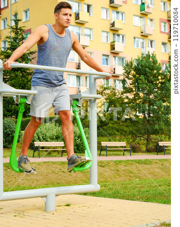 Man doing legs exercises in outdoor gym 119710084
