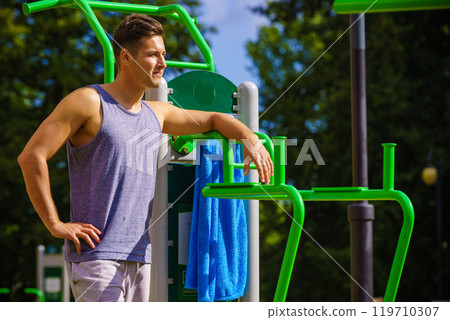 Man working out in outdoor gym Man working out in outdoor gym 119710307