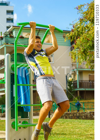 Man doing pull ups in outdoor gym 119710333