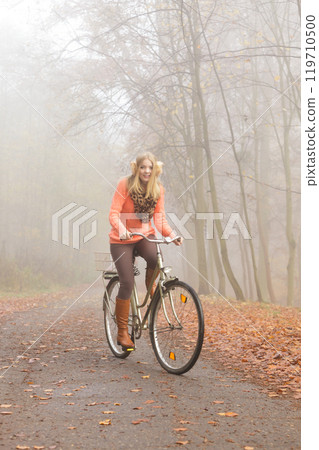 Active woman riding bike bicycle in autumn park. 119710500
