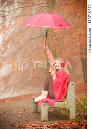 Girl sitting in park with umbrella Girl sitting in park with umbrella 119710512