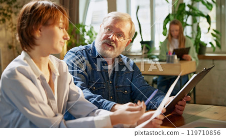 Experienced team leader explains charts and graphs, helping colleagues understand financial data and growth trends 119710856