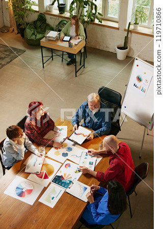 Interactive discussion led by senior leader, guiding team through strategic objectives and business goals. Aerial view. Interactive discussion led by senior leader, guiding team through strategic objectives and business goals. Aerial view. 119710866