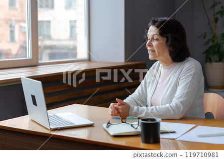 Happy middle aged senior woman sit with laptop talk on video call with friends family. Laughing mature old senior grandmother having fun talking speaking with grown up children online Happy middle aged senior woman sit with laptop talk on video call with friends family. Laughing mature old senior grandmother having fun talking speaking with grown up children online 119710981