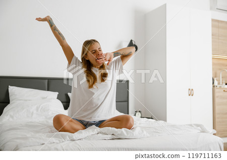 Engaging in a rejuvenating Morning Stretch Routine within a Cozy and Inviting Bedroom Setting 119711163