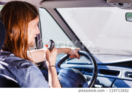 Young man driving car using cb radio 119711682