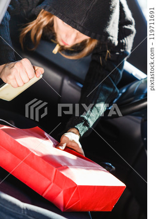 Burglar thief stealing smartphone and bag from car Burglar thief stealing smartphone and bag from car 119711691