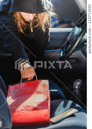 Burglar thief stealing smartphone and bag from car Burglar thief stealing smartphone and bag from car 119711693