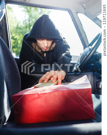 Burglar thief stealing smartphone and bag from car 119711695