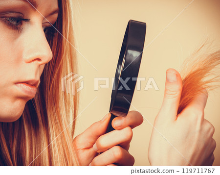 Sad woman looking at damaged hair ends. Sad woman looking at damaged hair ends. 119711767