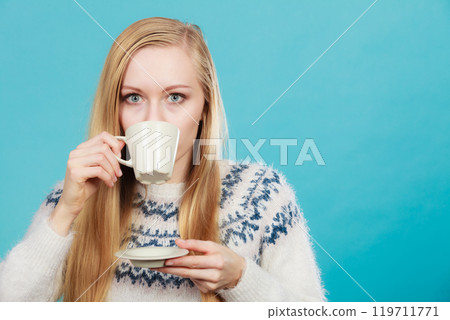 Blonde woman drinking hot drink from cup 119711771