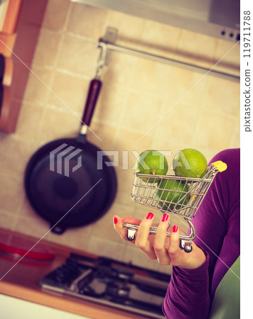 Woman holding shopping cart with limesinside Woman holding shopping cart with limesinside 119711788