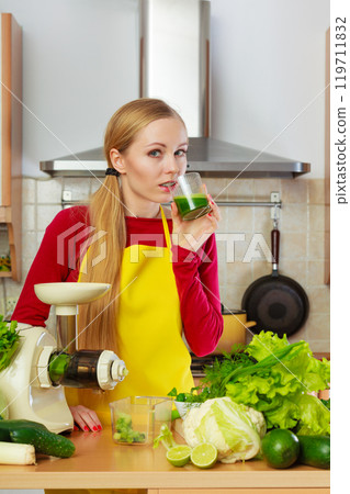 Woman in kitchen making vegetable smoothie juice 119711832