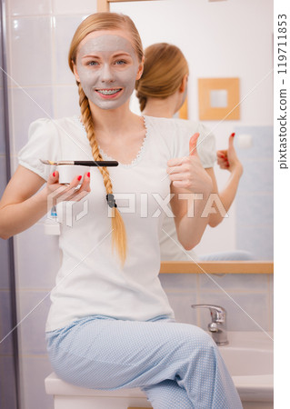 Happy young woman applying mud mask on face Happy young woman applying mud mask on face 119711853