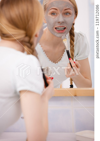 Woman with grey clay mud mask on her face Woman with grey clay mud mask on her face 119712086