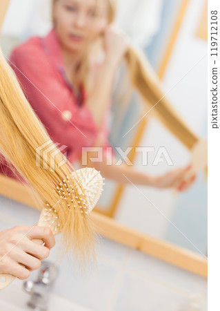Woman brushing her long hair in bathroom Woman brushing her long hair in bathroom 119712108