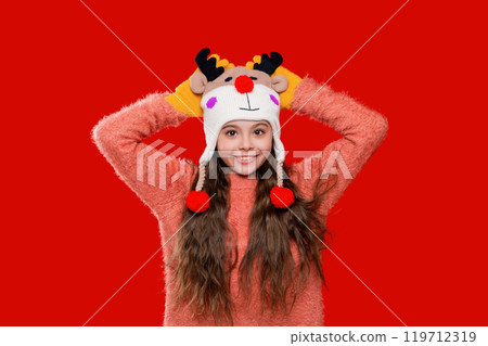 Winter child wardrobe. Teenage girl in Xmas hat isolated on red. Winter fashion for teenage style. Girl in knitted hat in winter season. Childhood lifestyle. Stylish earflap beanie Winter child wardrobe. Teenage girl in Xmas hat isolated on red. Winter fashion for teenage style. Girl in knitted hat in winter season. Childhood lifestyle. Stylish earflap beanie 119712319